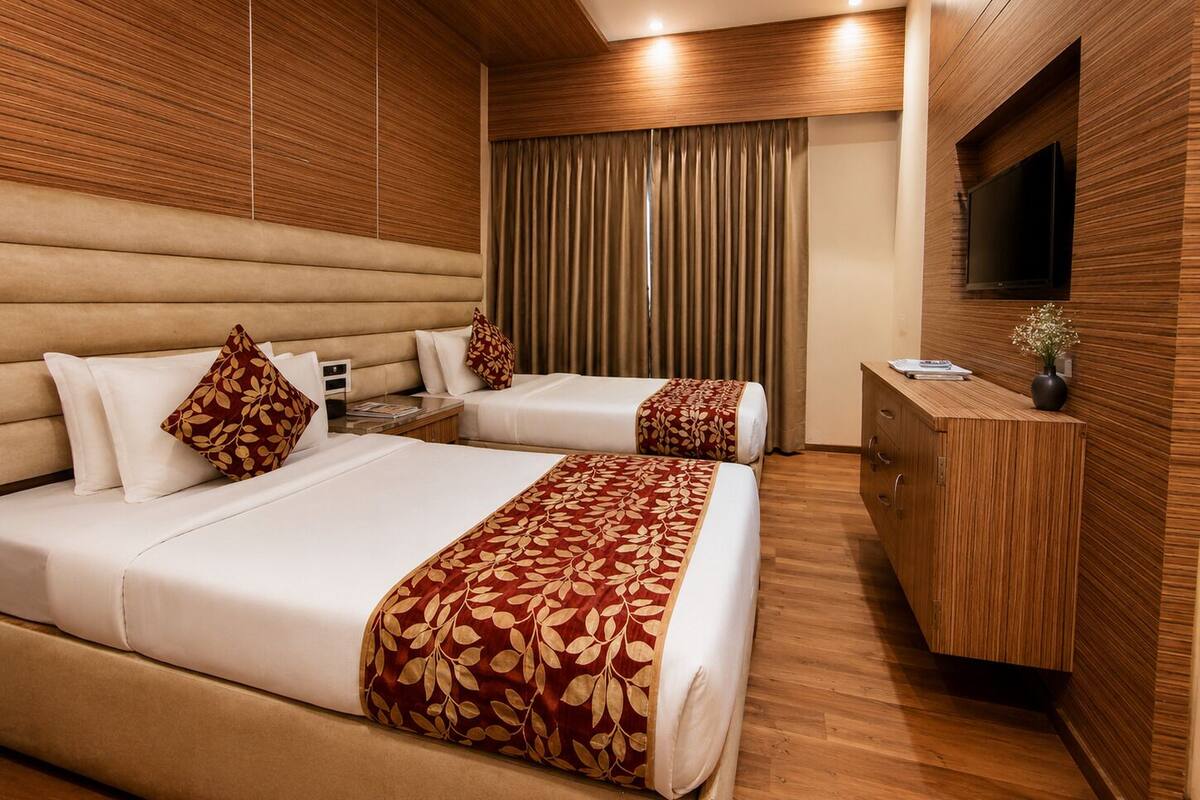 Habitación de hotel con dos camas, cabecero de madera, televisión de pantalla plana y escritorio de madera.