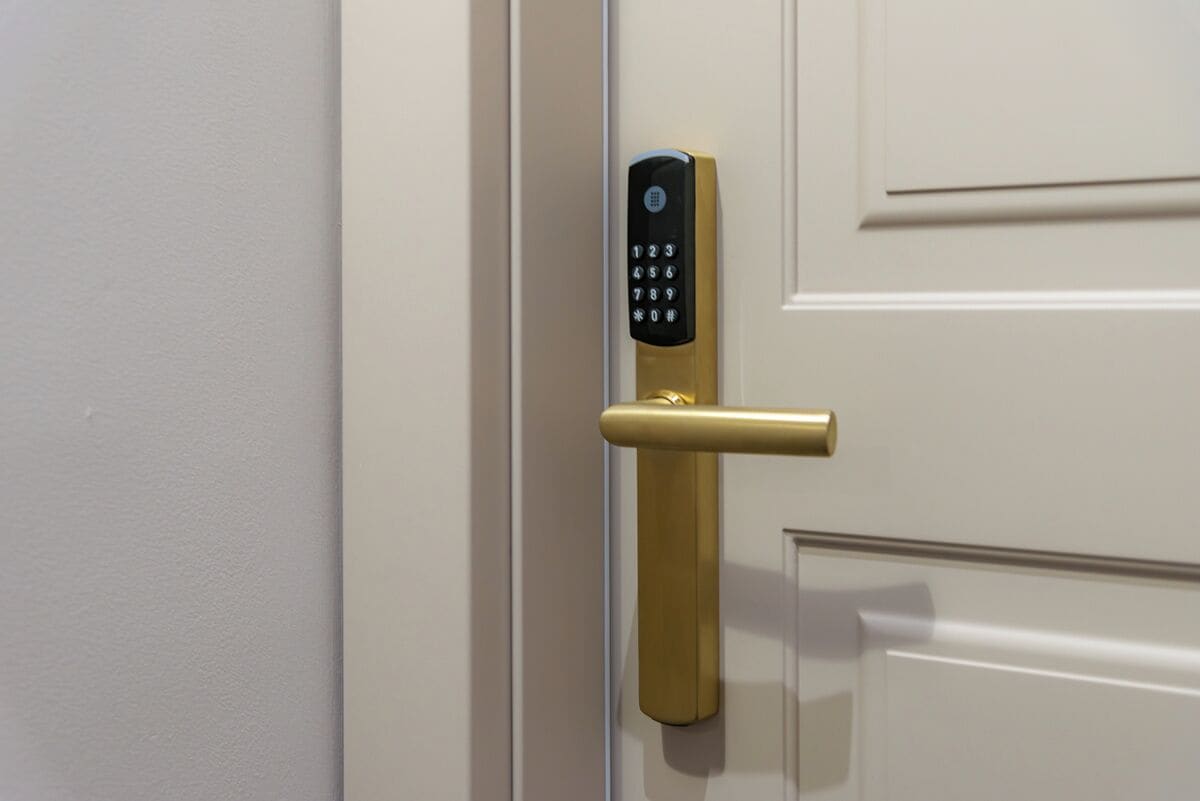 Une porte dotée d’un système de verrouillage électronique moderne à clavier et d’une poignée de couleur dorée.