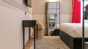 Een slaapkamer met een bed, een spiegel, een bureau en een kledingkast.