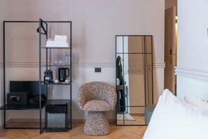 A hotel room with a mirrored wardrobe, a round upholstered chair, a small side table, and a bed with white bedding. - The Couper Duomo (Milan)