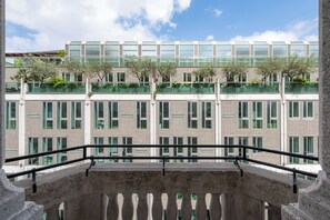 A multi-story building with a modern architectural style, featuring a balcony with greenery and a clear sky in the background. - The Couper Duomo (Milan)