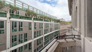 Een meerlaags gebouw met een modern ontwerp, met grote ramen en een balkon met beplanting.