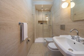 A modern bathroom with a shower, toilet, bidet, and sink. - The Couper Duomo (Milan)