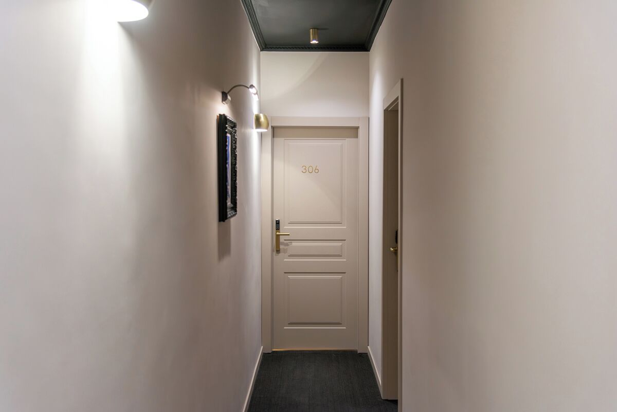 A narrow hallway with a door labeled '306,' a wall-mounted light fixture, and a doorbell.