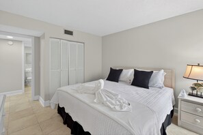 A bedroom with a bed, white curtains, a nightstand, and a lamp. - Steps to Beach, Sleeps 9, Walk to Coligny, 2 Kings, Bunk Room, 3 beds. 2.5 baths (Hilton Head Island)