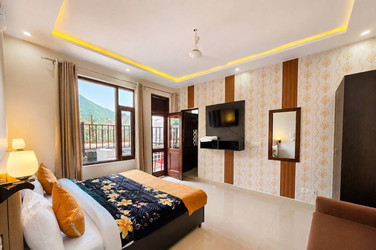 A hotel room with a bed, a TV, a mirror, and a balcony with a view.