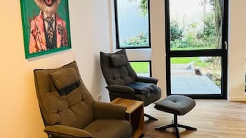 Ein modernes Wohnzimmer mit einem großen Fenster, einem grün gerahmten Gemälde eines Hundes und einem Holztisch.