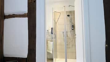 Ein modernes Badezimmer mit Duschkabine aus Glas, weißen Wänden und Holzboden.
