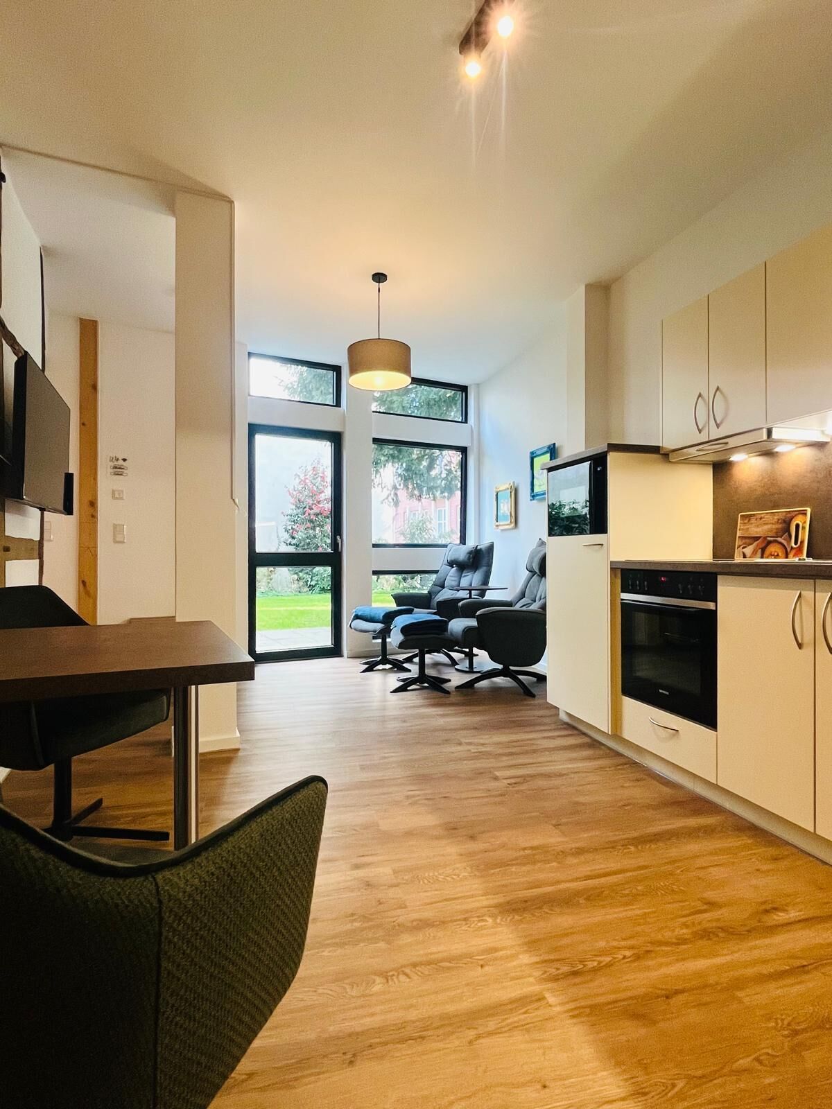 Een moderne keuken met houten vloeren, een eethoek met een tafel en stoelen, en een zithoek met een bank en fauteuils.