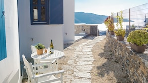 Un edificio blanco con un sendero de piedra, una mesa con sillas y plantas en macetas.
