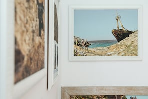 Ett inramat fotografi som föreställer ett skeppsvrak på en stenstrand, med en klar himmel i bakgrunden.