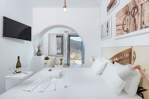 Quarto de hotel moderno com cama, televisão, uma garrafa de vinho e vista por um arco.