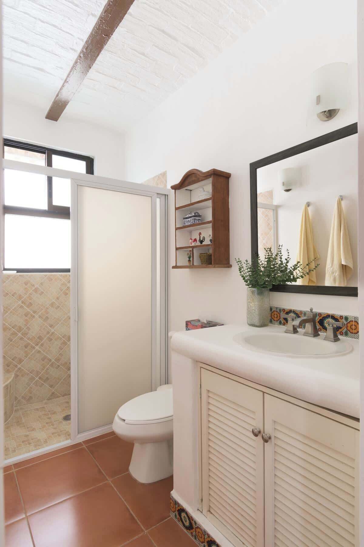 A bathroom with a shower, toilet, sink, and a mirror.