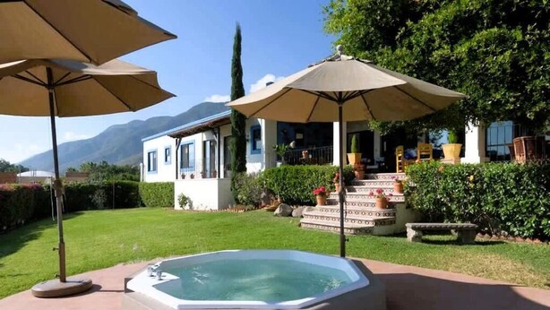 Un jacuzzi en un jardín, con una casa al fondo.