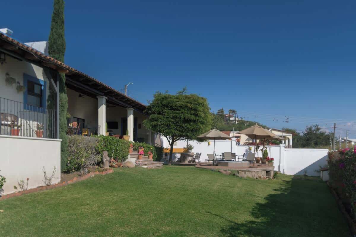 A residential property with a well-maintained lawn, a patio with outdoor furniture, and a large tree providing shade.