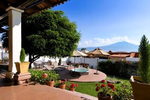 Un patio con mobiliario exterior, una bañera de hidromasaje y vistas a la montaña.