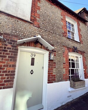A brick building with a white door labeled '39' and a window with a plant outside. - 3 bedroom cottage with garden in Arundel (West Sussex)