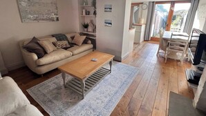 Un salón con sofá, mesa de centro y vistas al exterior.