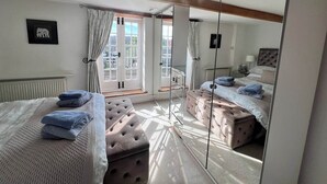 Un dormitorio con dos camas, un espejo grande y una ventana con cortinas.