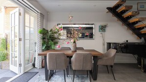 Ein Essbereich mit einem Holztisch, sechs Stühlen, einer Blumenvase, einem großen Spiegel und einer Treppe.