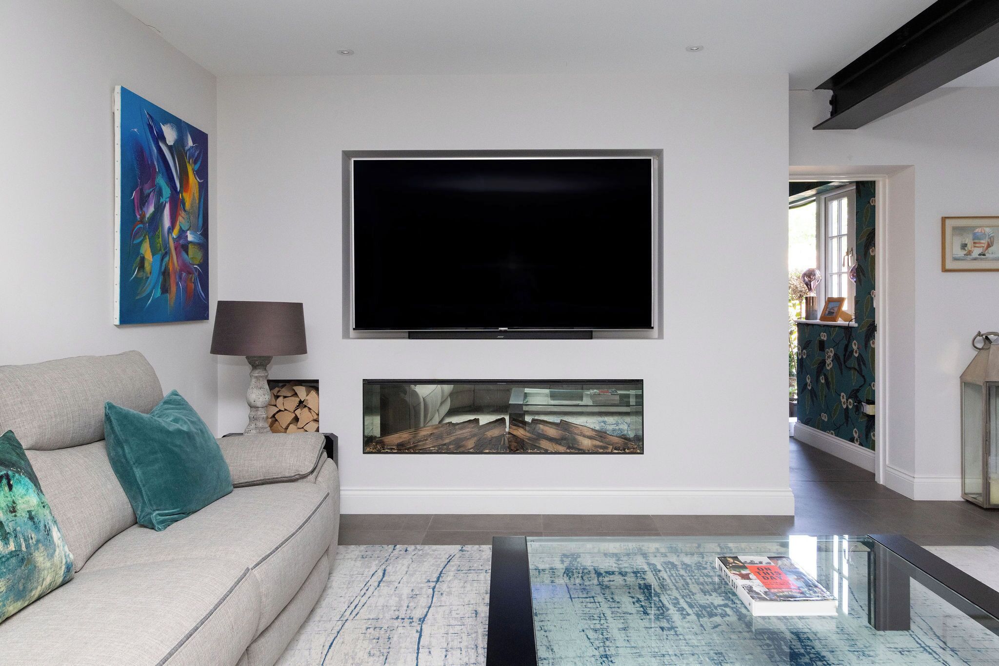 A living room with a sofa, a flat-screen TV, a painting, and a fireplace.