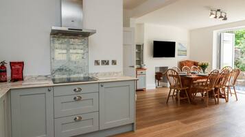 A modern kitchen with a marble countertop, grey cabinetry, and a stainless steel range hood.