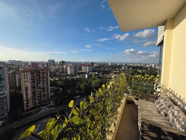 Ein Balkon mit Blick auf eine Stadtlandschaft, darunter Wolkenkratzer und Grünflächen.