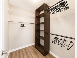 A walk-in closet with open shelves, a metal rod for hanging clothes, and a wooden floor. - Alfredo Retreat at Spanish Springs (The Villages)
