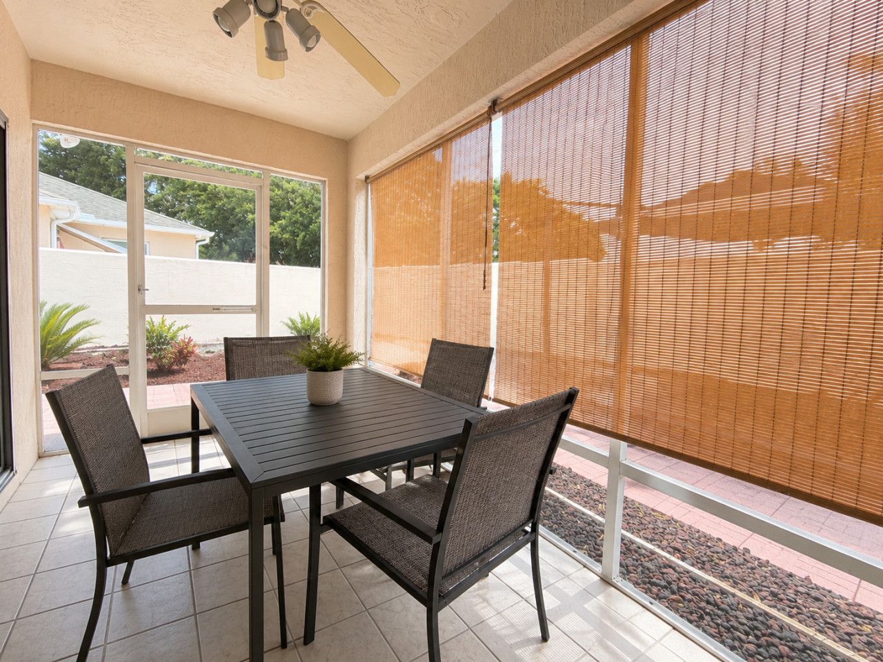 A covered patio with a table and chairs, a ceiling fan, and a view through large windows.
