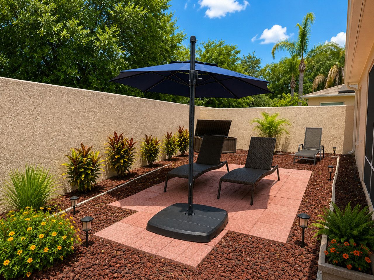 A patio with a table and chairs, a blue umbrella, and potted plants.