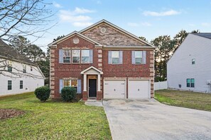A two-story brick house with a front garage, a small front porch, and a well-maintained lawn. - Peaceful&Spacious Retreat for the Whole Family (Hampton)