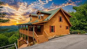 Eine Holzdiele mit Balkon, Satellitenschüssel und Blick auf den umliegenden Wald.