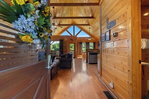 Ein Holzblockhaus im Inneren mit Essbereich, einer Couch und einer Küche.