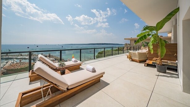 A balcony with lounge chairs, a potted plant, and a view of the sea. - Exceptional penthouse - panoramic view (Cannes)