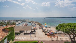 A marina with boats, a beach area, and a building with a tiled roof. - Exceptional penthouse - panoramic view (Cannes)