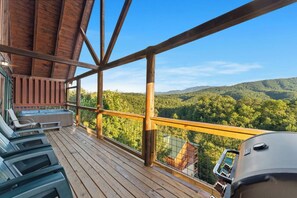 A wooden deck with outdoor seating and a hot tub overlooking a forested landscape. - Amazing Rocky Top Views: Vistas That Wow (Pigeon Forge)