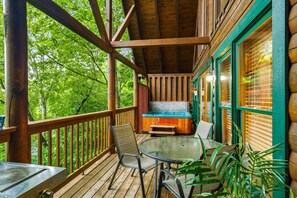 A wooden deck with a hot tub, chairs, and a table.
