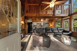 A spacious living area with a sectional sofa, a glass coffee table, and a ceiling fan. - Ridge Retreat: Life's Better on the Ridge (Pigeon Forge)