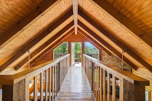 Ein Dachzimmer mit einer Holztreppe, die zu einem Balkon führt.