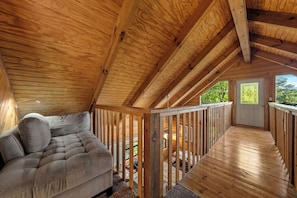 A wooden interior with a sofa and a balcony. - Ridge Retreat: Life's Better on the Ridge (Pigeon Forge)