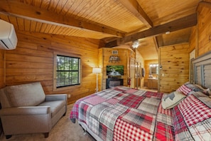 Ein gemütliches Cabin-Zimmer mit einem Bett, einem Sessel, einem Fernseher und einem Fenster.