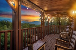 Une terrasse en bois offrant une vue sur les montagnes et un coucher de soleil.