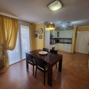 A dining area with a table and chairs, a kitchen with white cabinets, and a sliding glass door. - El Rincon 5 - spacious apartment in beautiful complex (Los Cristianos)