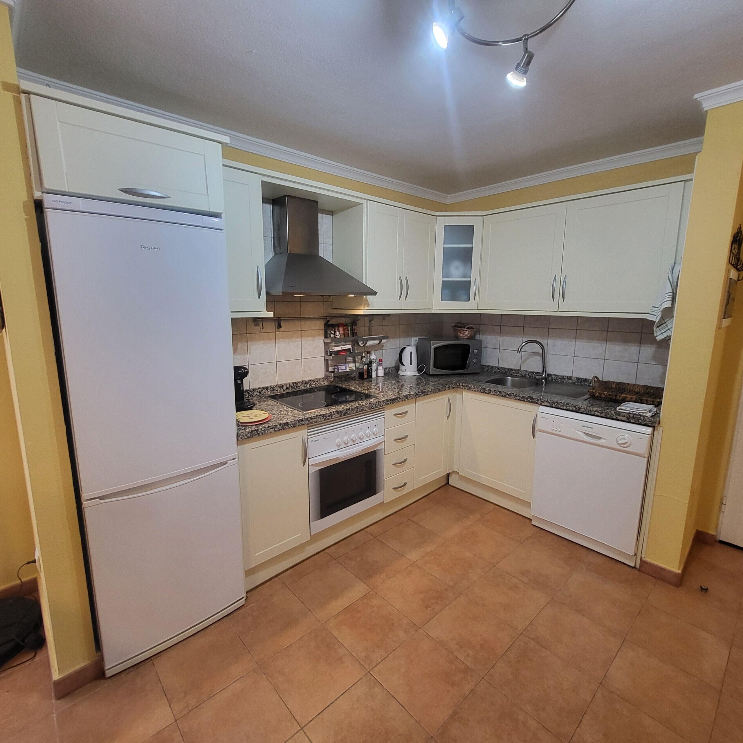 A compact kitchen with white cabinets, a built-in oven, a microwave, and a dishwasher.