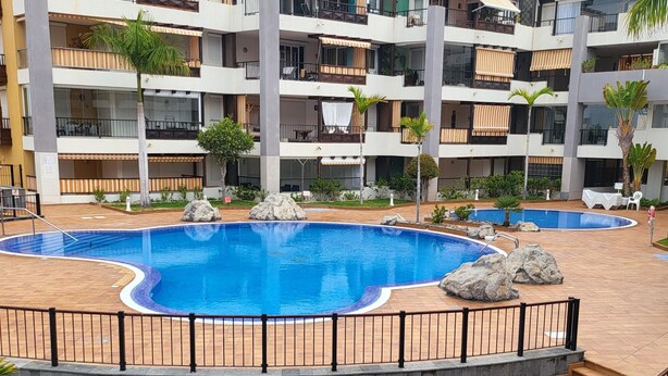 Un hotel de varios pisos con piscina central, asientos al aire libre y una escalera que conduce a los pisos superiores.