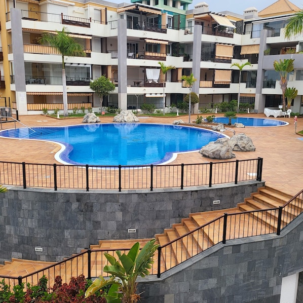 A multi-story hotel with a central swimming pool, outdoor seating, and a staircase leading to upper floors. - El Rincon 5 - spacious apartment in beautiful complex (Los Cristianos)