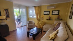 Una sala de estar con sofá, una mesa de centro, una silla y un comedor con sillas.