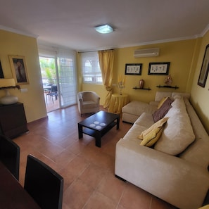 A living room with a sofa, a coffee table, a chair, and a dining area with chairs. - El Rincon 5 - spacious apartment in beautiful complex (Los Cristianos)
