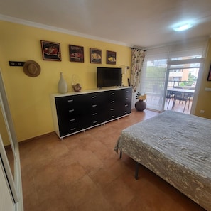 A bedroom with a bed, a dresser, a TV, and a balcony with outdoor furniture. - El Rincon 5 - spacious apartment in beautiful complex (Los Cristianos)