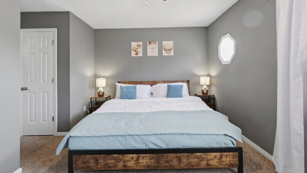 Une chambre à coucher avec un lit en bois, un ventilateur de plafond, des lampes fixées au mur et une porte.